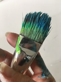 Hand hält Pinsel mit türkiser Farbe